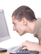 Man typing on keyboard and staring into monitor of desktop computer.